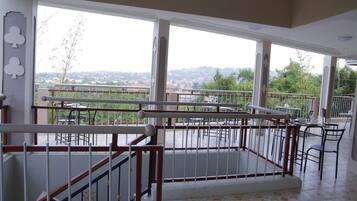 A balcony with a view of a cityscape, featuring a railing and outdoor seating.