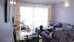 A living room with a dining table, chairs, a sofa, and a coffee table. - Crystal Hotel Apartments Entebbe (Entebbe)