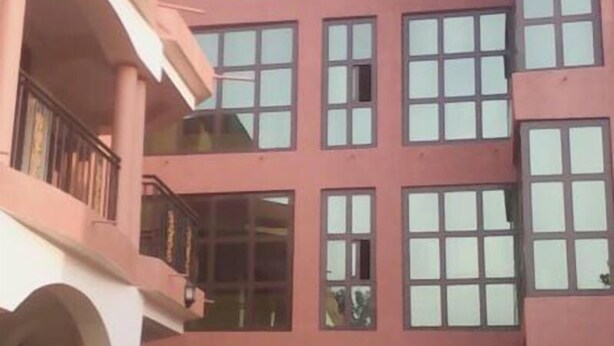A multi-story building with a pink facade, large windows, and a balcony on the second floor.