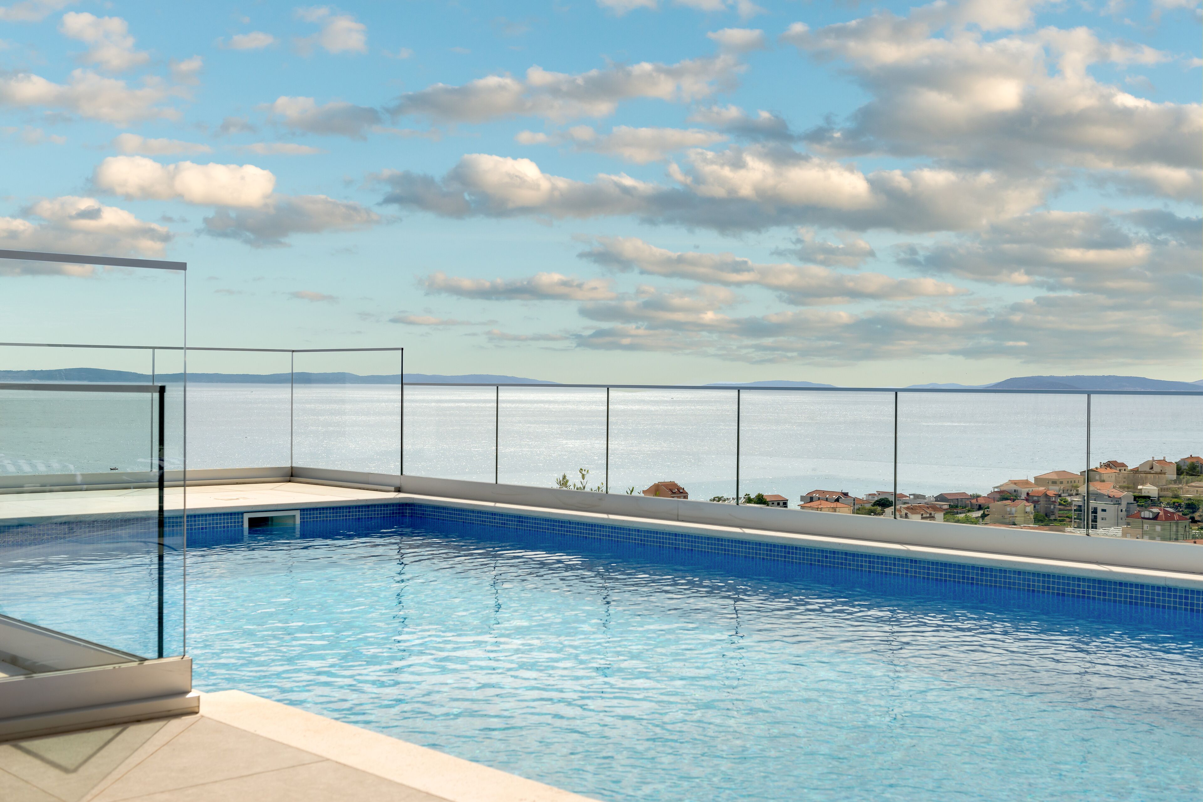 A swimming pool with a clear view of the sea and distant hills.