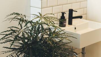 A bathroom with a white sink, black faucet, and a potted plant.