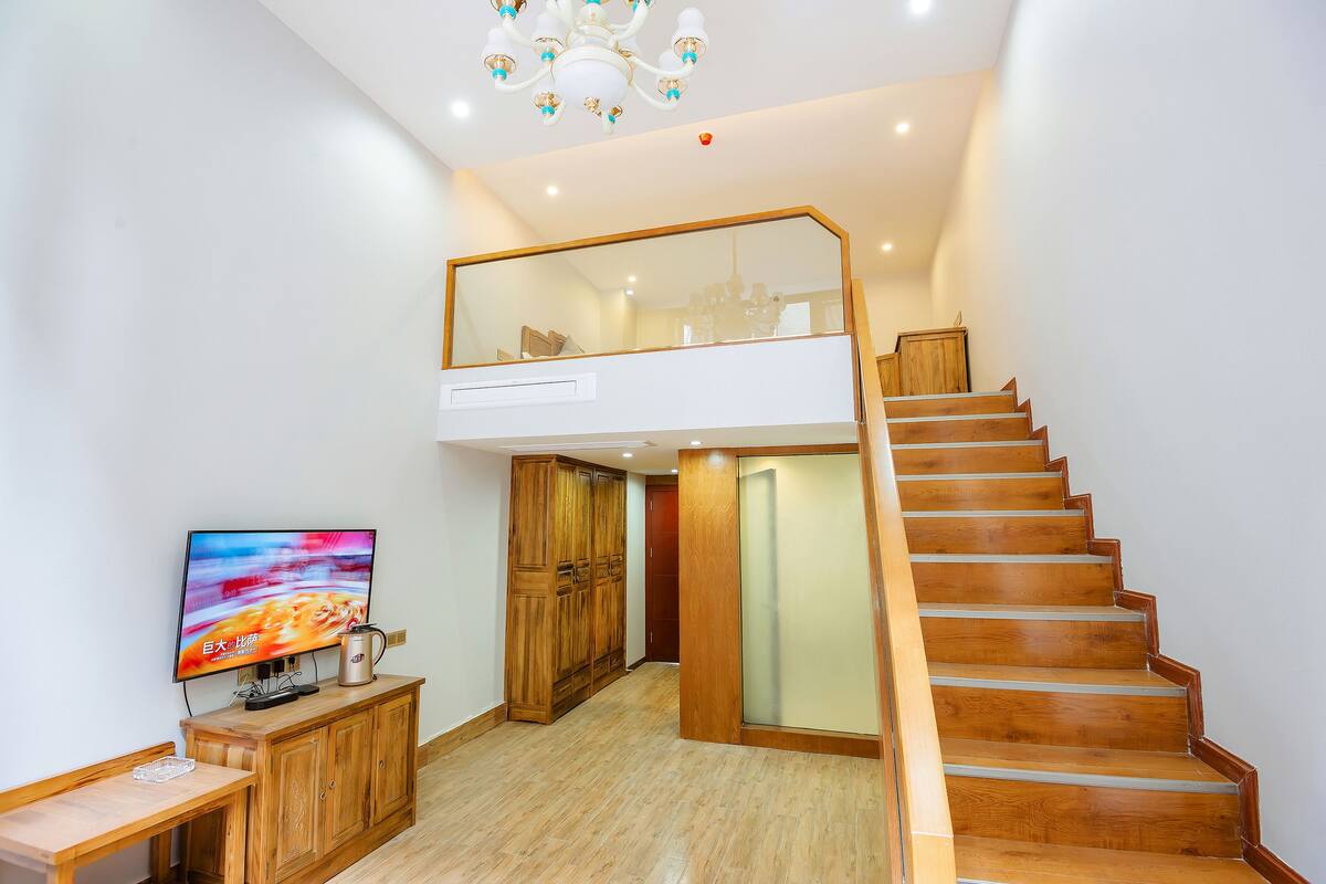 A spacious room with a wooden staircase, a television, and a cabinet.