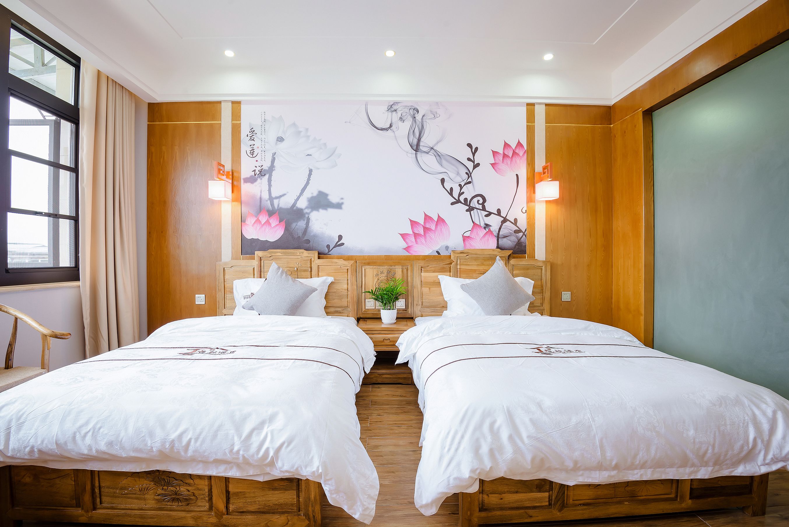 A hotel room with two beds, wooden headboards, a large floral mural on the wall, and a window with curtains.