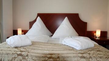 A neatly made bed with a patterned bedspread, two pillows, and two rolled towels.