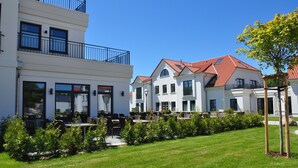 Un hôtel moderne à la façade blanche, aux toits recouverts de tuiles rouges et doté d’une terrasse.