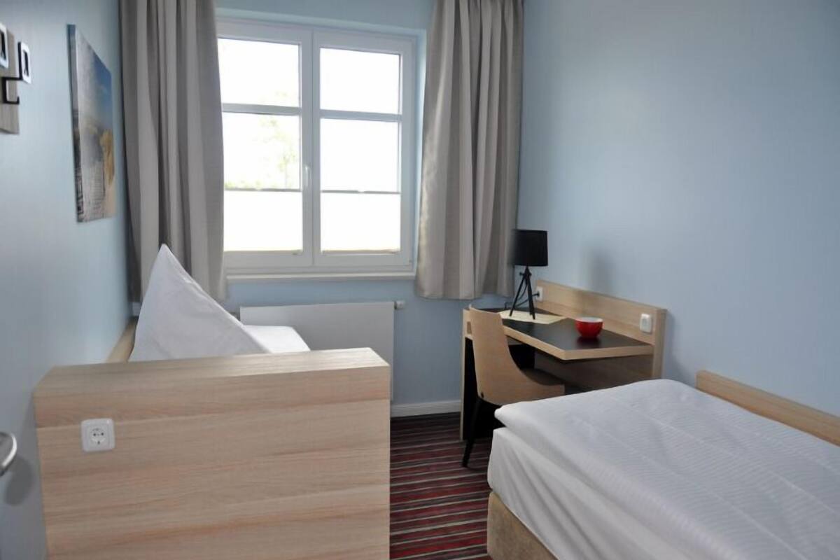 Une chambre d’hôtel avec un lit, un bureau et une fenêtre.