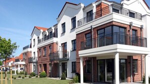A modern residential building with brick and white facades, large windows, and balconies. - Avalon Ferienwohnungen Bellevue (Fehmarn)
