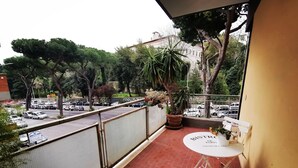 A balcony with a red-tiled floor, a white table with a sign reading "BISTRO DE PARIS," and a yellow cushioned chair. - Maison Giulivia a San Pietro (Rome)