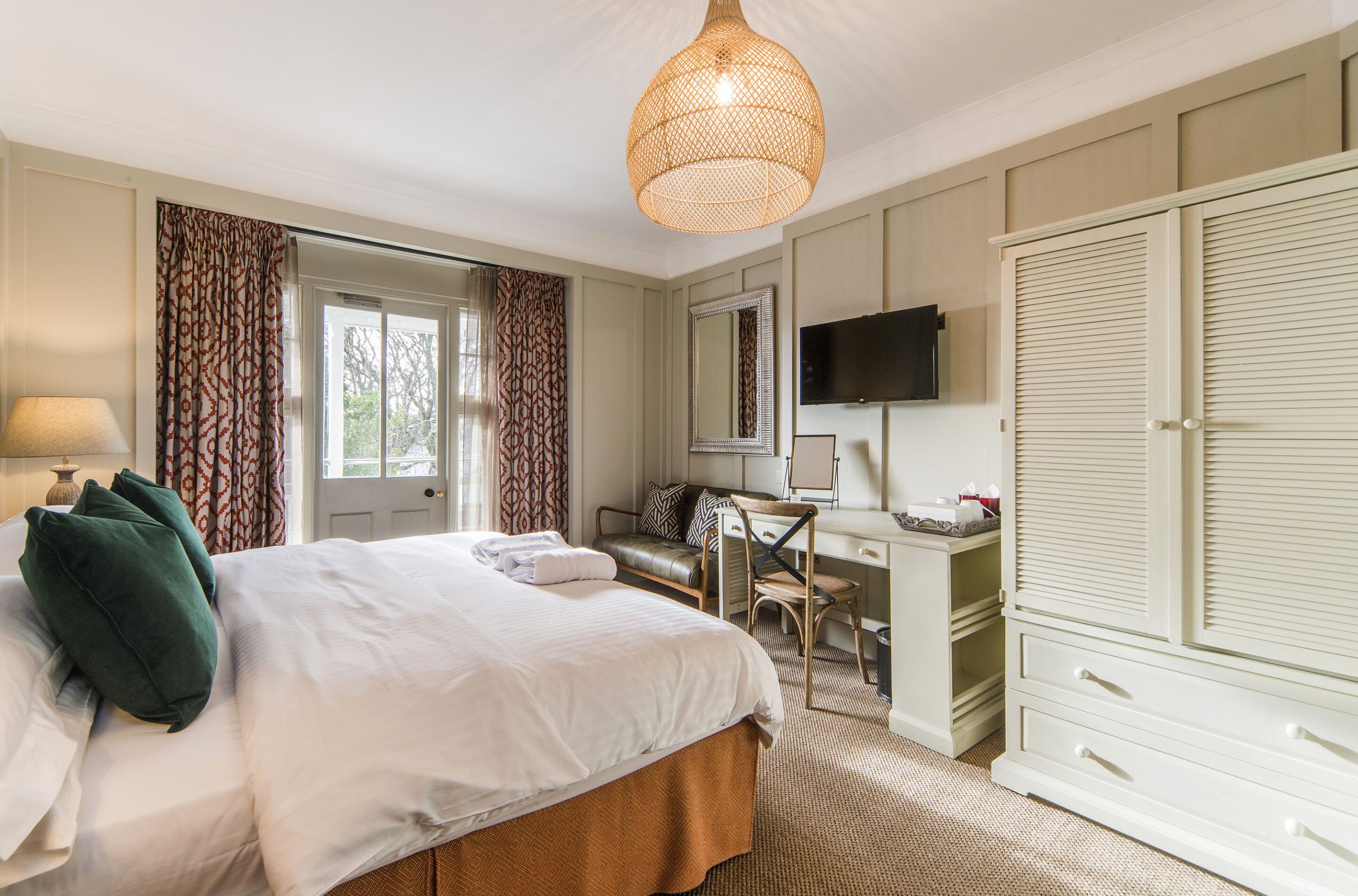 Una habitación de hotel con cama, escritorio, silla, armario y televisor.