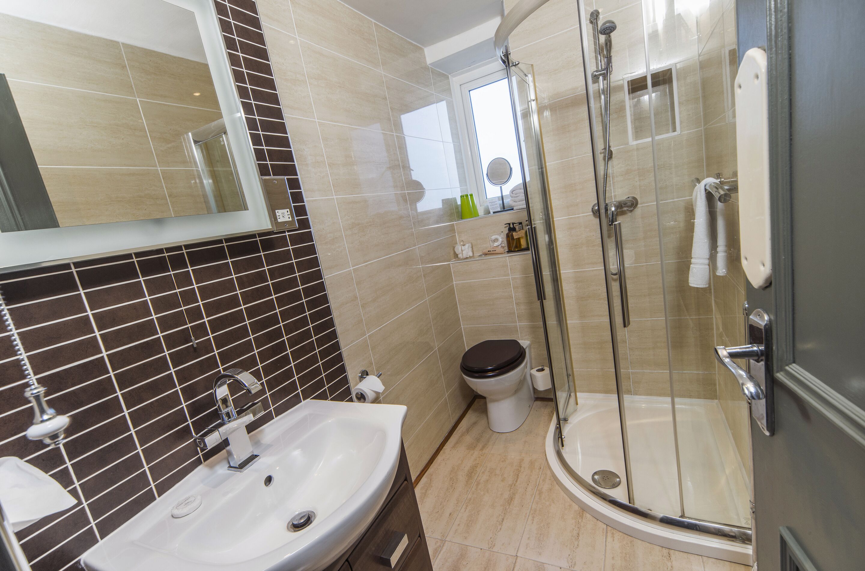 A modern bathroom with a glass-enclosed shower, a sink, and a toilet.