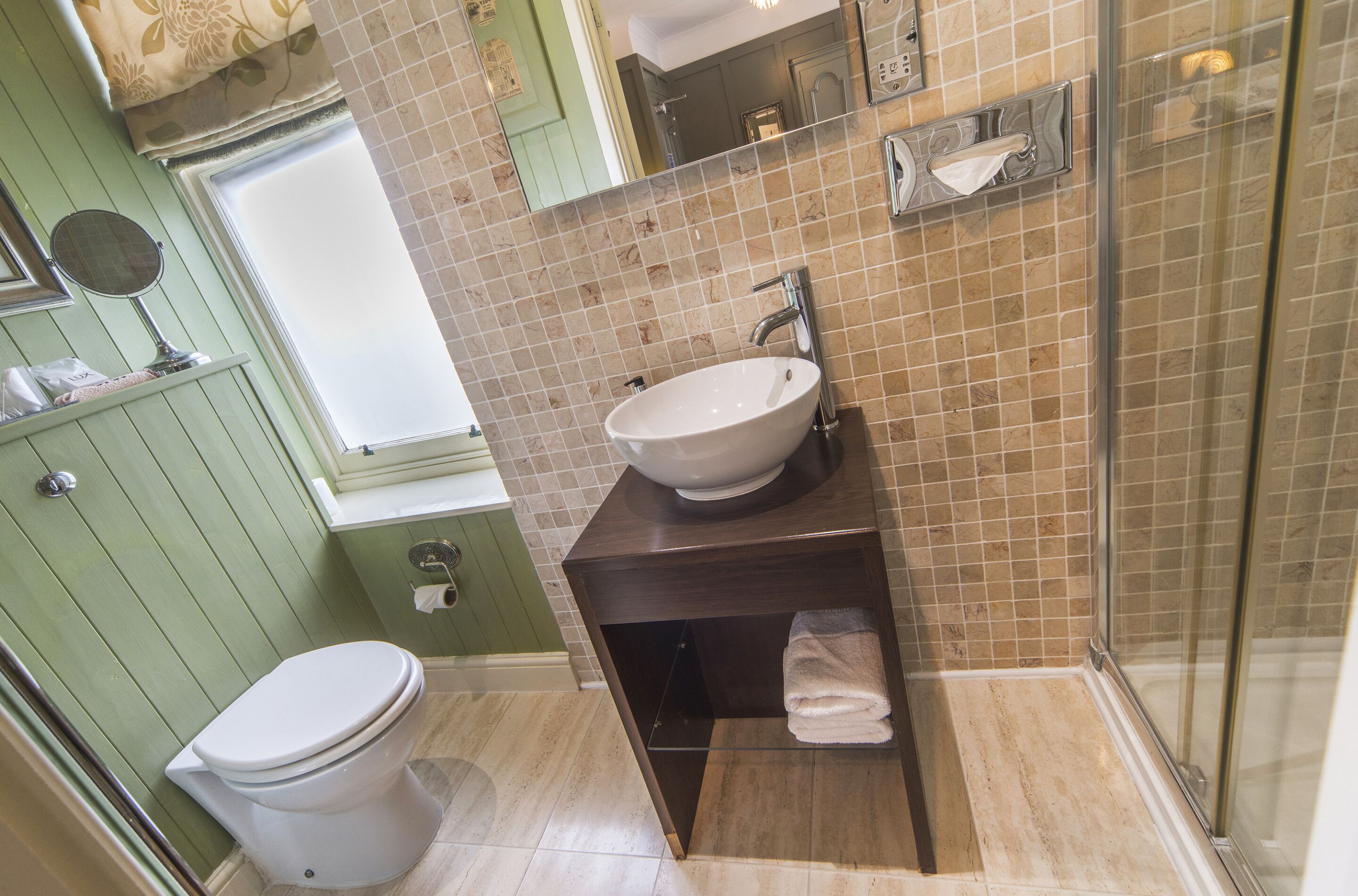 A bathroom with a white toilet, a sink with a mirror, and a shower area.