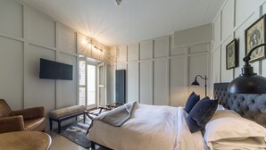 Een moderne slaapkamer met een groot bed, een flatscreen televisie, een bankje en een bureau.