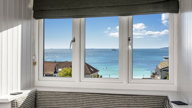 Een uitzicht op zee en gebouwen vanuit een raam.