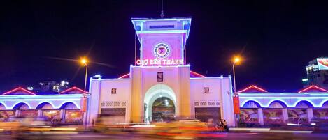 A building with a clock tower, illuminated signage, and arched entrances.