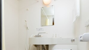 A small, white bathroom with a toilet, sink, and shower. - Kansai Seaside Hotel (Kaizuka)