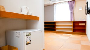 A compact kitchen with a refrigerator, wooden shelves, and a window with curtains. - Kansai Seaside Hotel (Kaizuka)