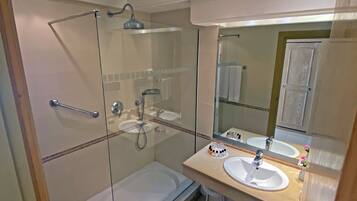 Un bagno moderno con doccia vetrata, due lavandini e uno specchio grande.