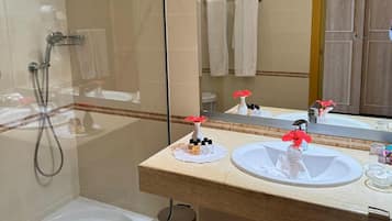 Un baño con ducha envuelta en vidrio, bañera blanca y tocador con lavamanos y espejo.