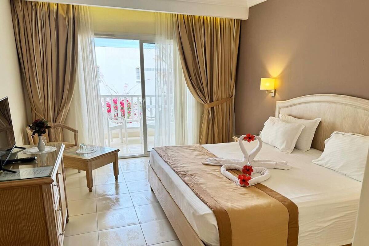 Une chambre d’hôtel avec un lit, un bureau, une chaise et une vue sur l’extérieur.