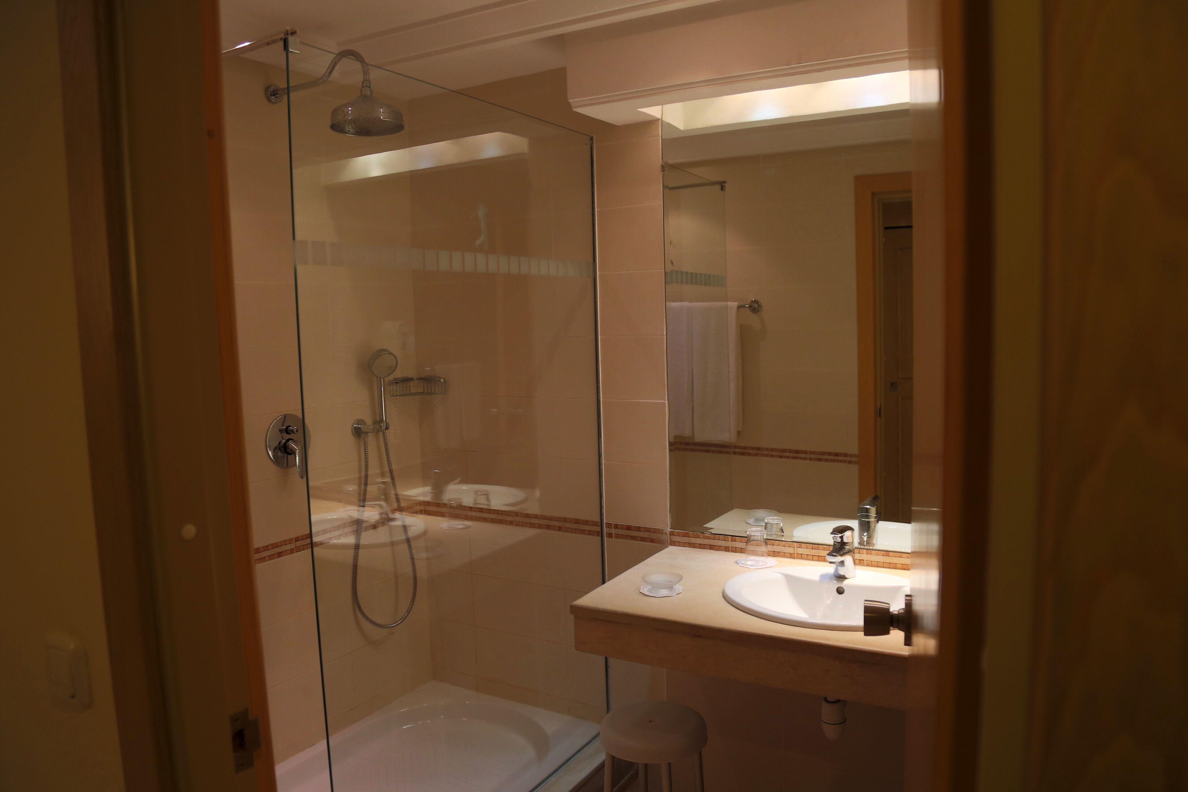 A modern bathroom with a glass-enclosed shower, a bathtub, and a vanity with a sink and mirror.
