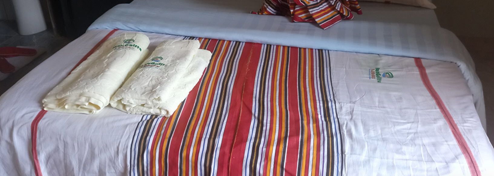 A bed with a striped bedspread and two neatly folded towels.