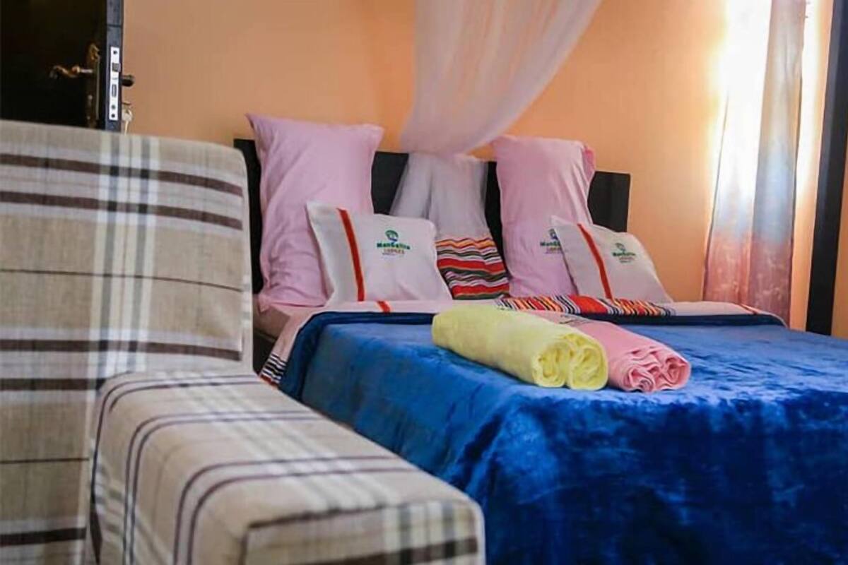 A hotel room with a bed, a chair, and a window with curtains.