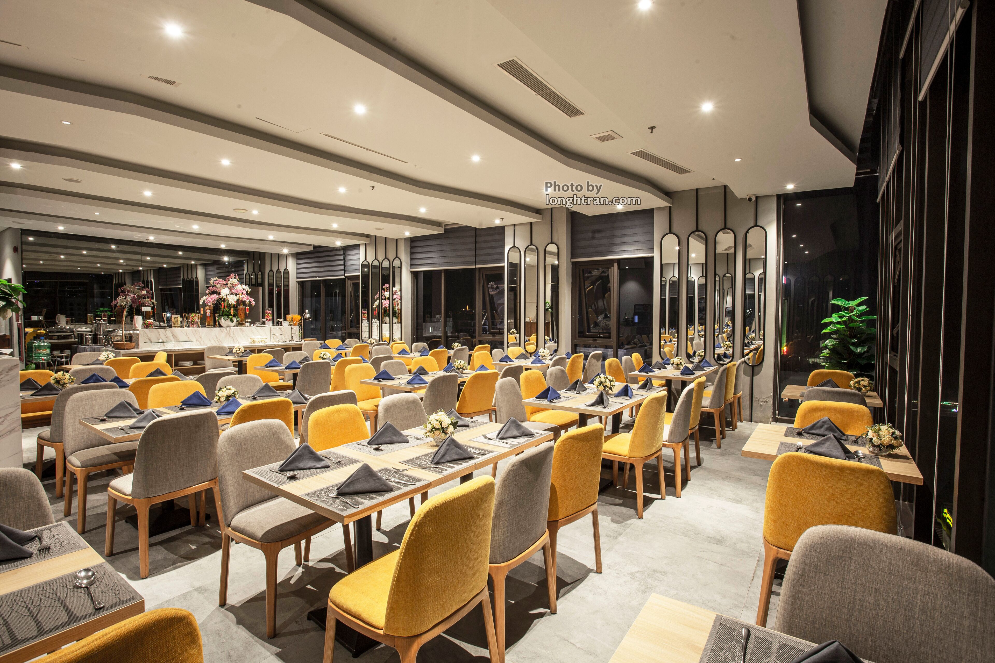 A spacious conference room with multiple tables and chairs, large windows, and a modern interior design.