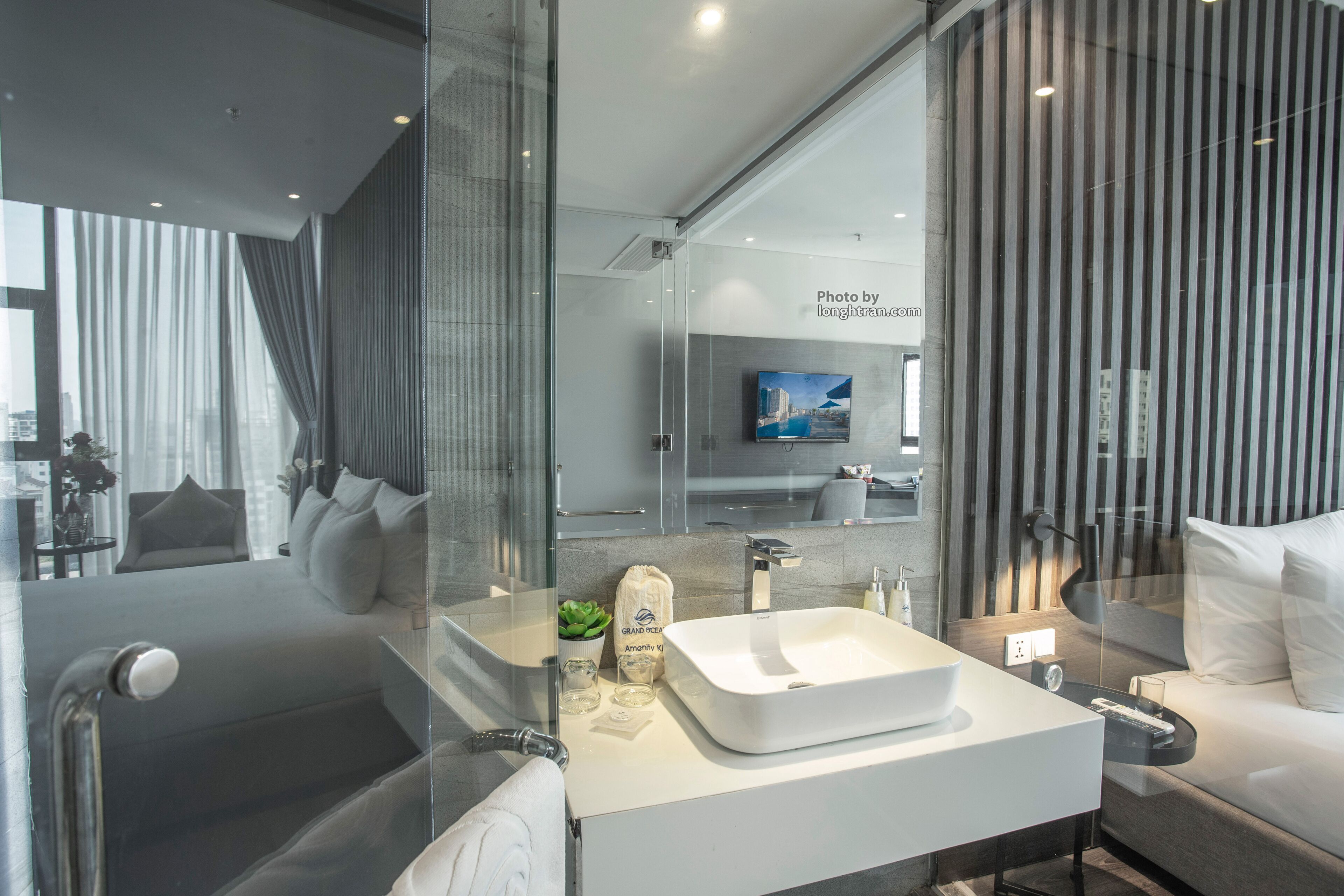A modern bathroom with a large mirror, a white sink, and a glass shower enclosure.