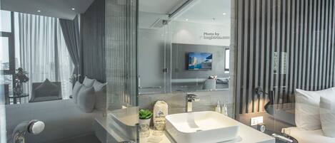 A modern bathroom with a large mirror, a white sink, and a glass shower enclosure.