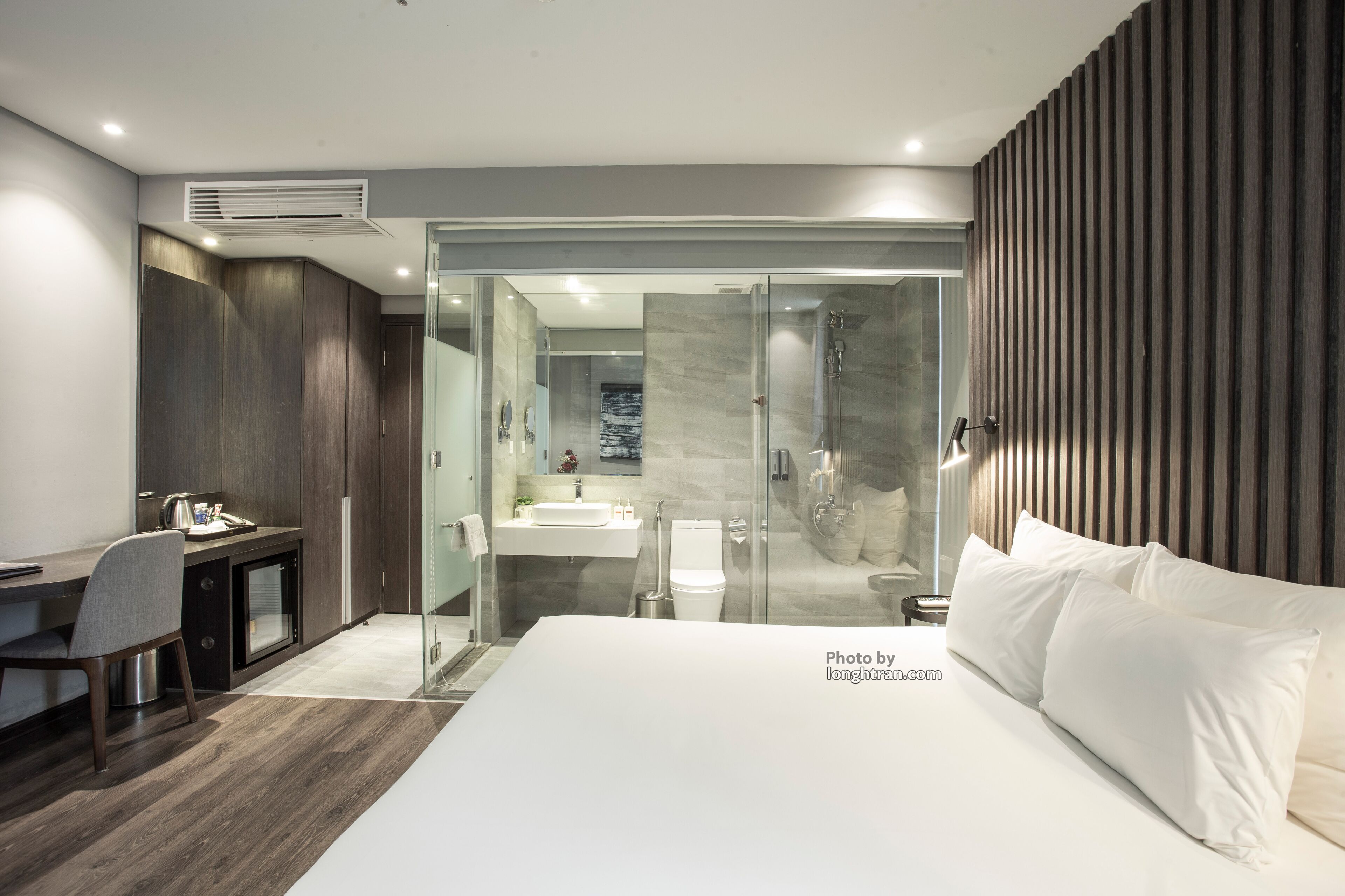 Ein modernes Hotelzimmer mit einem großen Bett, einem Schreibtisch und einer Dusche.