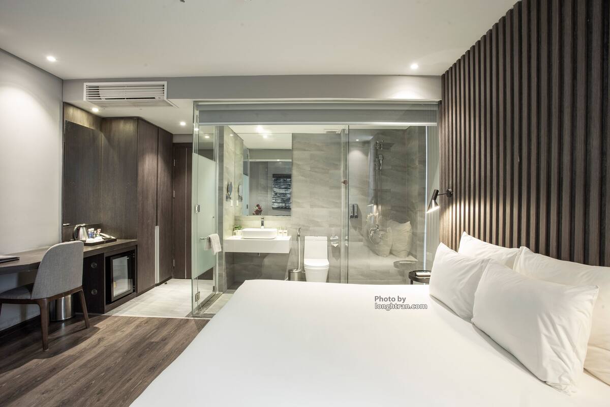 Una habitación de hotel moderna con una cama grande, un escritorio y una zona de ducha.