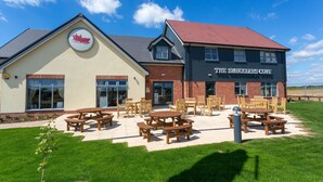 A building with a sign reading "The Smugglers Cove" and outdoor wooden picnic tables.