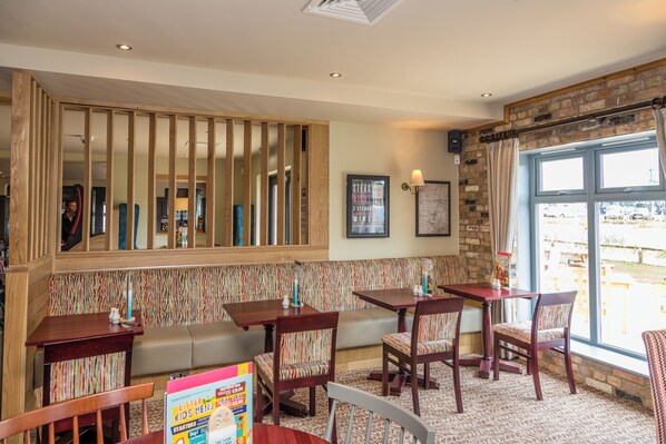 Un restaurant avec des meubles en bois, un mur à rayures et une grande fenêtre donnant sur un beau paysage.