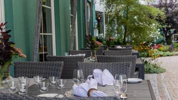 Un espace extérieur aménagé pour les repas, avec des meubles en osier et une table dressée pour deux personnes.