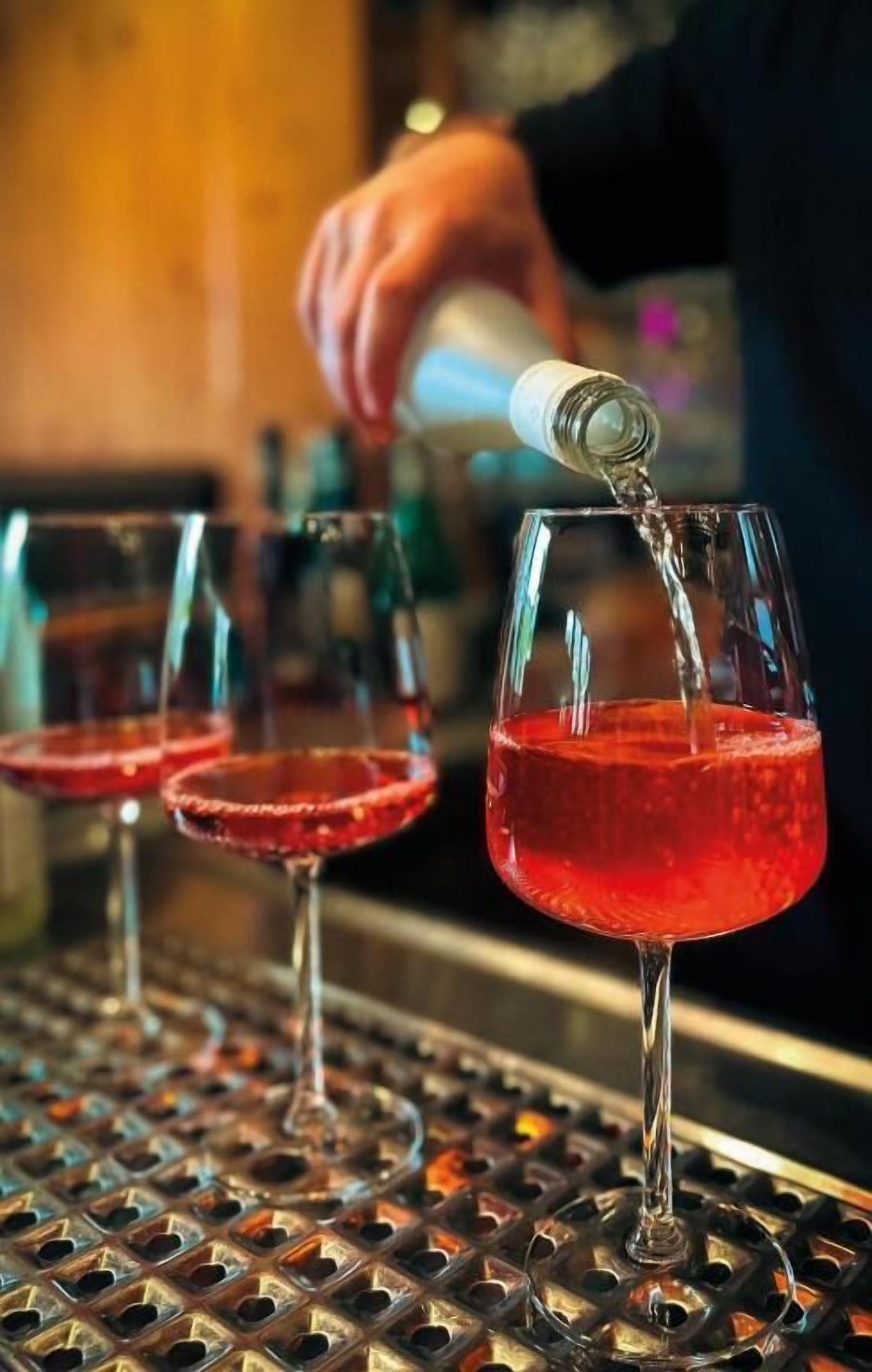 A bartender pouring a red drink into a glass.