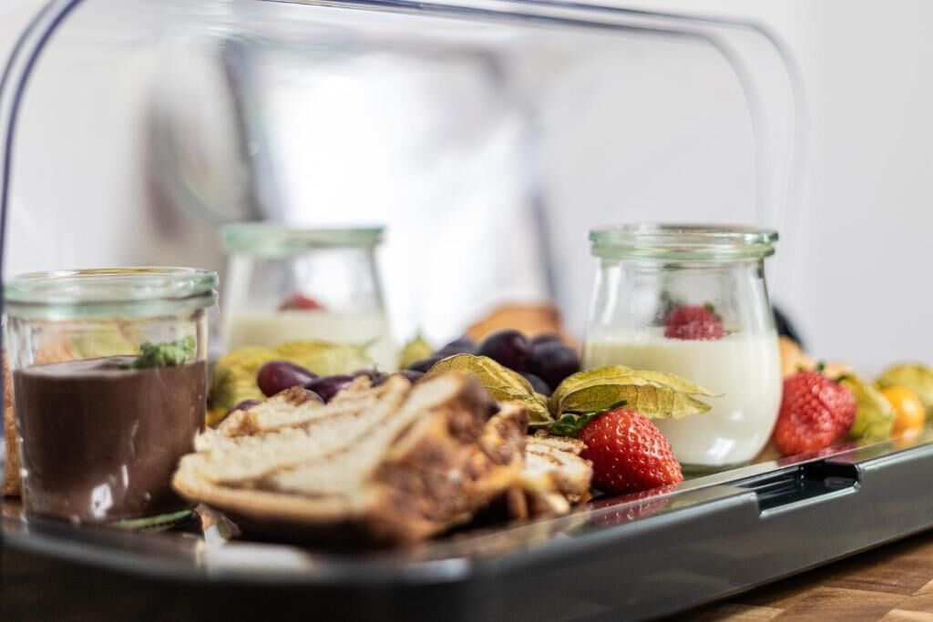 Eine Schale mit geschnittenem Fleisch, Obst und zwei kleinen Gläsern Schokolade und Joghurt.