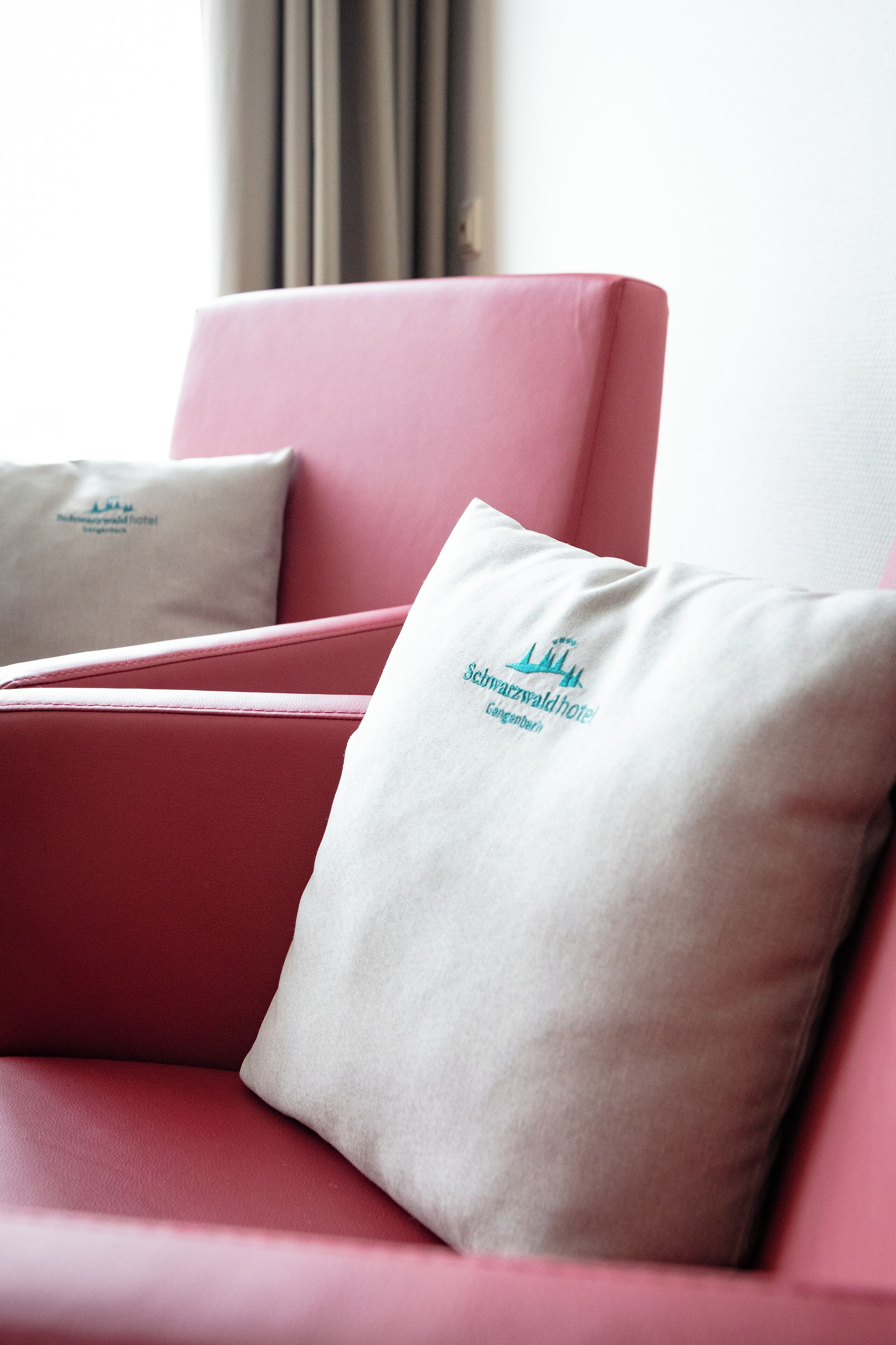 Un sofá rojo con un cojín que muestra el logotipo del Hotel Schwazwald.
