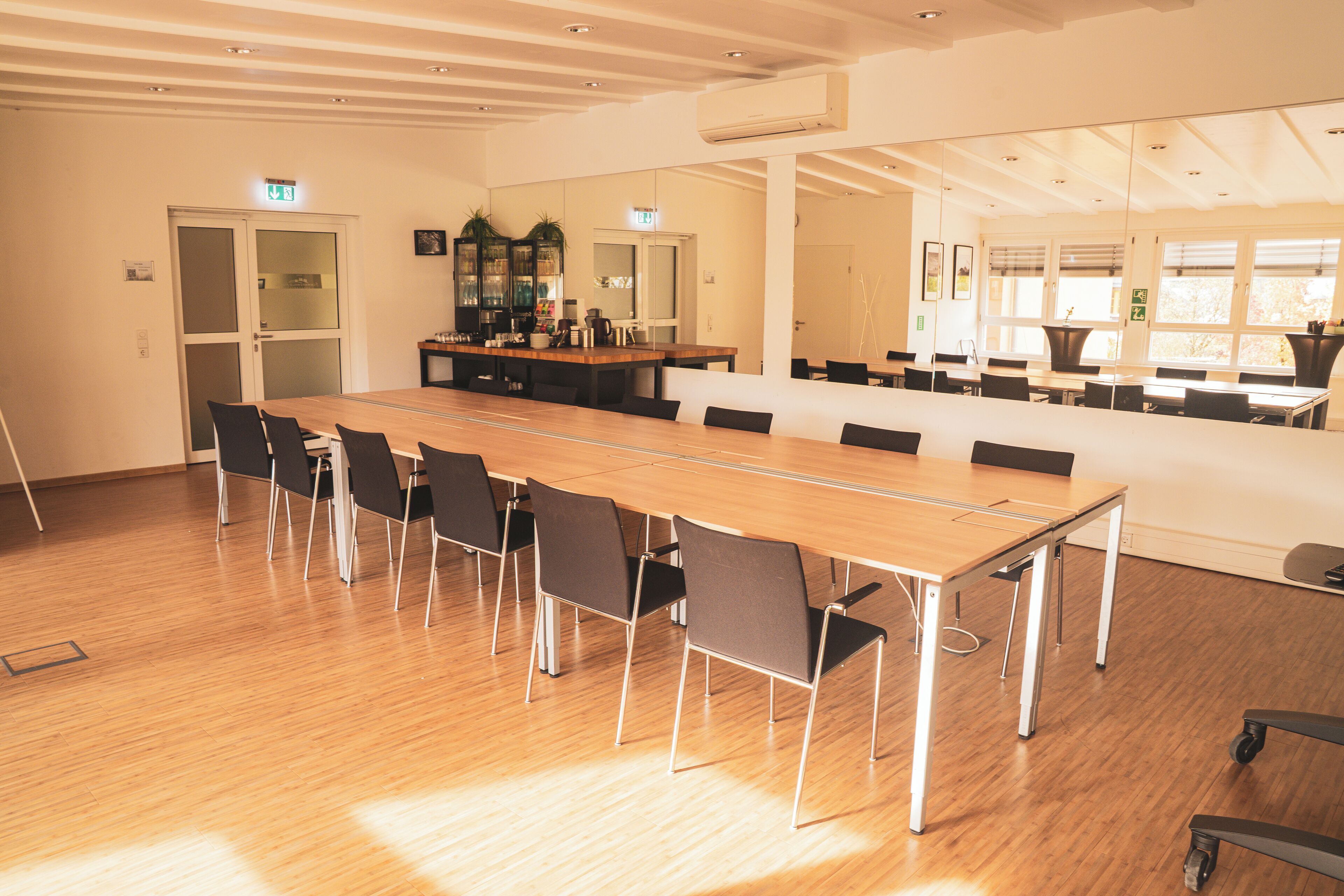 A conference room with a long table, chairs, and a small kitchenette area.
