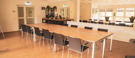 A conference room with a long table, chairs, and a small kitchenette area.