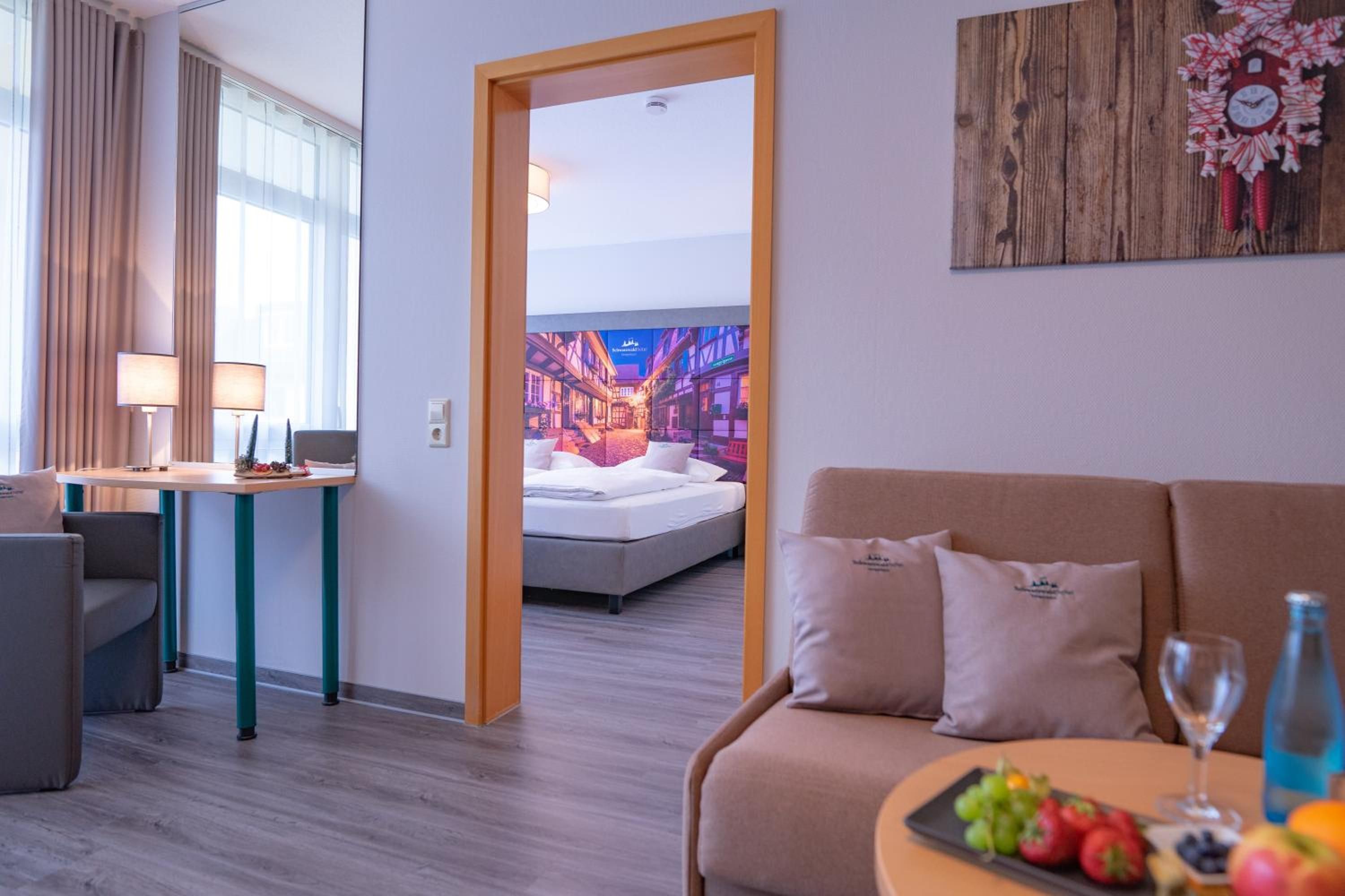 Una habitación de hotel con una cama, un área de descanso con sofá y una mesa, y una pared decorada con un reloj.