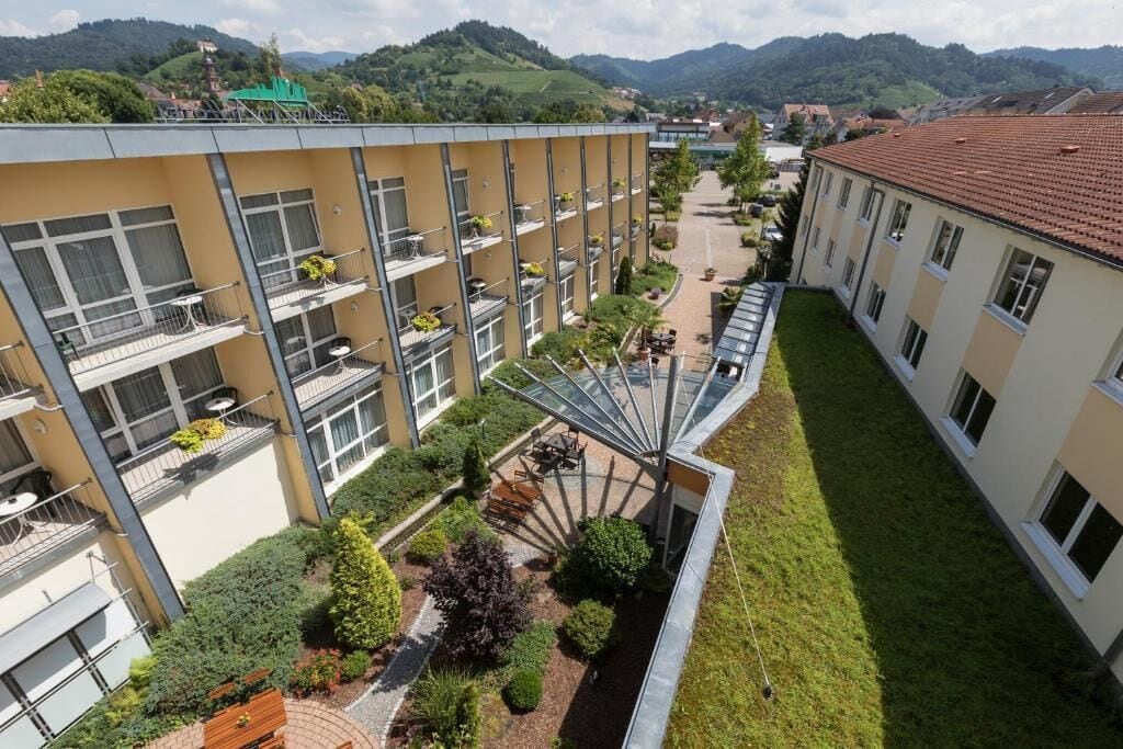 A multi-story hotel with balconies, a central courtyard, and a view of the surrounding hills.