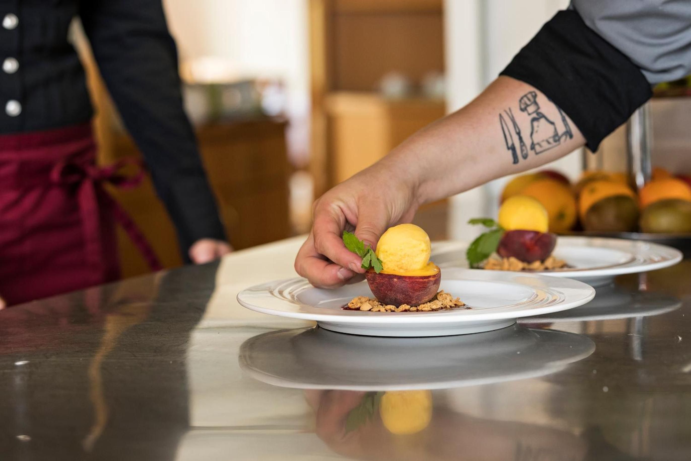 A person serving a dessert on a plate with a fruit-based presentation.