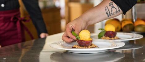A person serving a dessert on a plate with a fruit-based presentation.