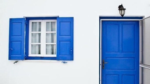 A blue door with a window above it, a light fixture above the door, and a stone-patterned floor. - Apartment Alex for 4 (Mykonos)