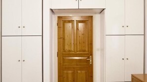 A room with white wardrobes, a wooden door, and a wooden dresser. - Apartment Alex for 4 (Mykonos)