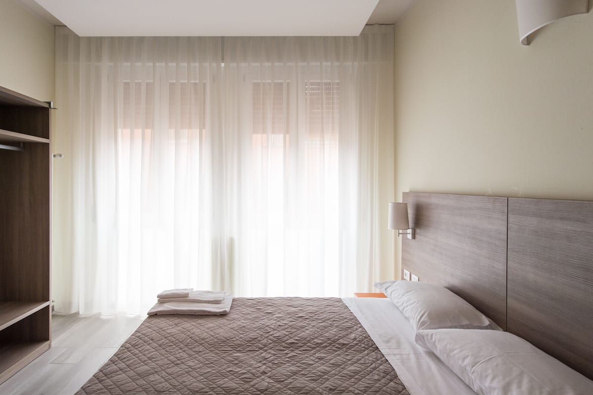 A neatly arranged bedroom with a bed, a bedside table, and a wardrobe.