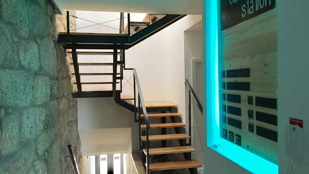 A staircase with wooden steps and metal railings, leading to a landing with a sign reading "campanha station".