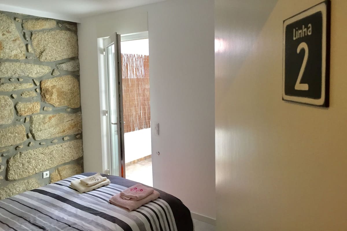A bedroom with a stone wall, a bed with striped bedding, and a sign indicating room number 2.