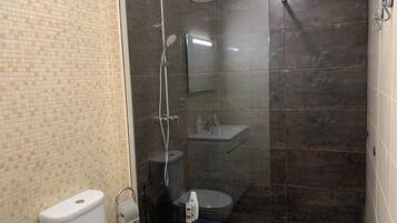 Un baño con ducha de vidrio, inodoro y lavamanos.