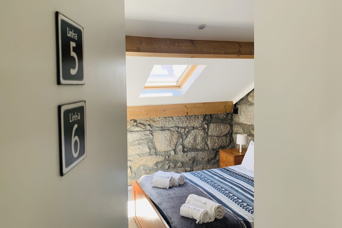 A bedroom with a skylight, a stone wall, and two signs indicating room numbers 5 and 6.